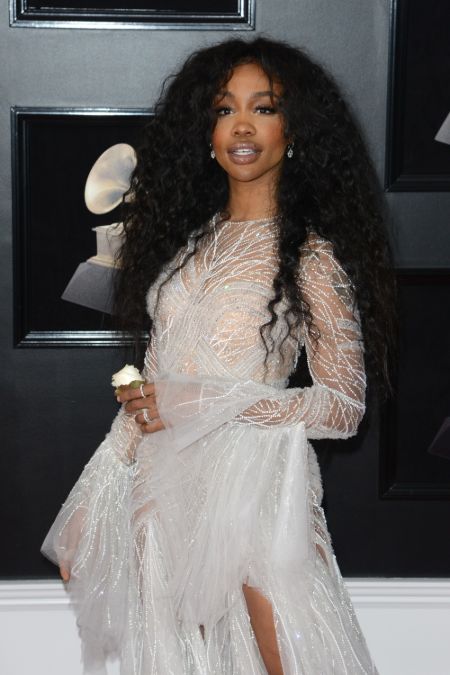 SZAwith open hair wearing a white sparkly gown on the grammy red carpet 